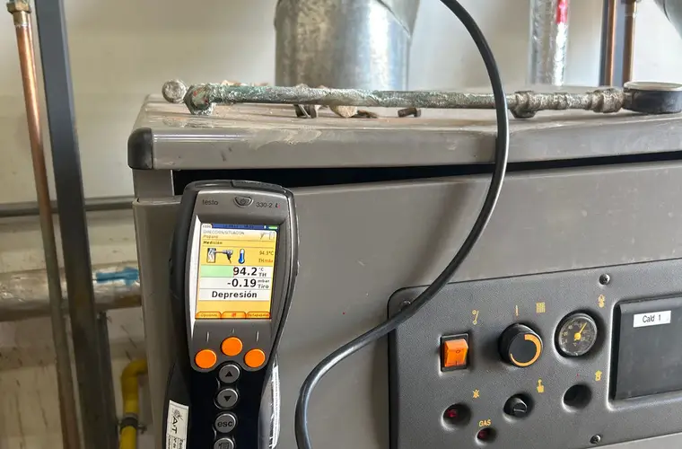 Analizador de combustión conectado a una caldera a gas, con la pantalla encendida